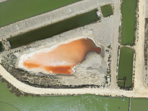 Aerial view of striking geometric patterns of salt evaporation ponds, displaying a spectrum of colors from ochre to green, Vejer de la Frontera, Andalusia, Spain.