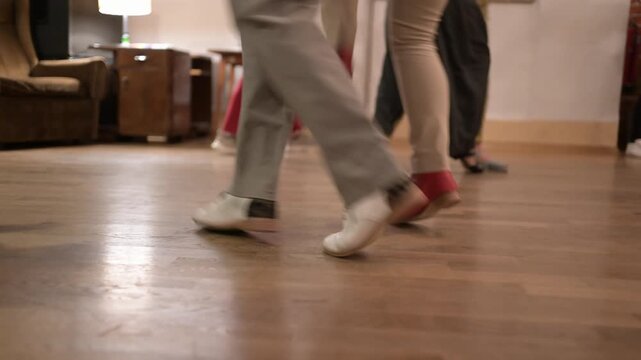 close up of swing dancers feet moving in rhythm on wooden floor. Elegant shoes and dynamic footwork in indoor social dance environment with vintage vibe.