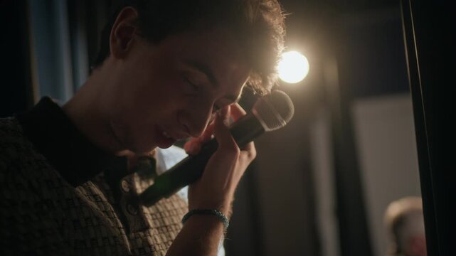 Tilt down shot of focused young adult male comedian revising text of speech on clipboard while rehearsing backstage before performance