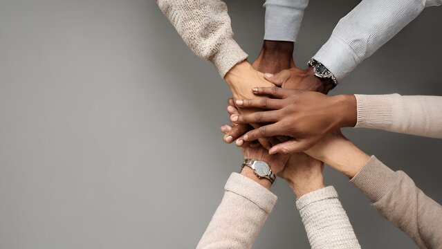 Professionals forming a central hand pile to convey support, mentoring, partnership and shared responsibility