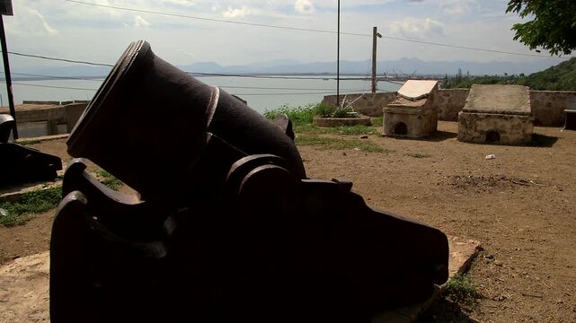 Historic 18th-century French cannon positioned at Fort Picolet overlooking the Caribbean Sea near Cap-Ha&iuml;tien, surrounded by weathered stone batteries and grassy hilltop.