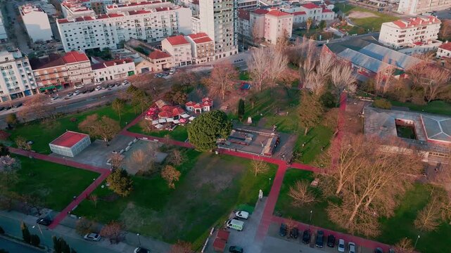 Drone shot rising and pulling back over Parque do 25 Abril in Rio Maior Portugal showing people, the city in the background, and the Natural Park of Serras de Aire e Candeeiros.
