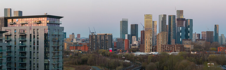 Obraz premium Aerial panorama featuring modern apartment blocks and the dense skyscraper cluster of Deansgate Square at dusk, Manchester, UK.