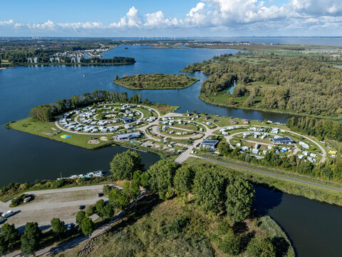 Aerial view of the campsite with trailers, surrounded by water and lush green trees, Almere, Netherlands.