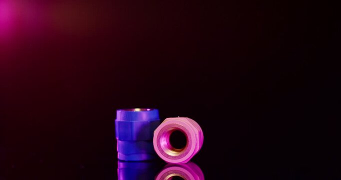 Blue and pink plastic threaded pipe connectors and industrial fittings on a dark background with red ambient light