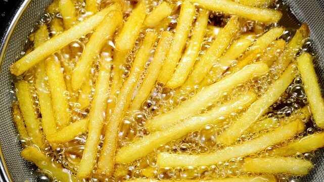 French fries being deep fried in hot oil in a kitchen