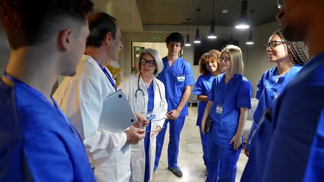 Professional medical team. Including senior doctors and young interns. Having a meeting in a hospital hallway. The diverse group of healthcare workers are collaborating and discussing a patient case