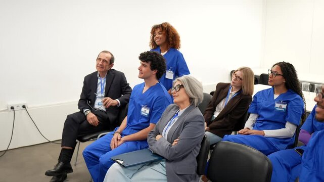 Diverse group of doctors and nurses sitting in an audience and listening attentively during a medical training seminar, engaging in continued professional education and knowledge sharing