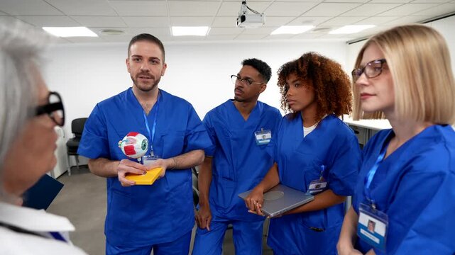 Multiethnic group of medical students listening to a male professor explaining the anatomy of the human eye with a model during a lesson in a modern hospital conference room