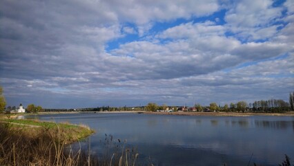 Fototapeta premium Panoramiс spring landscape of Zdvizh river with dramatic cloudy sky in Makariv, Ukraine