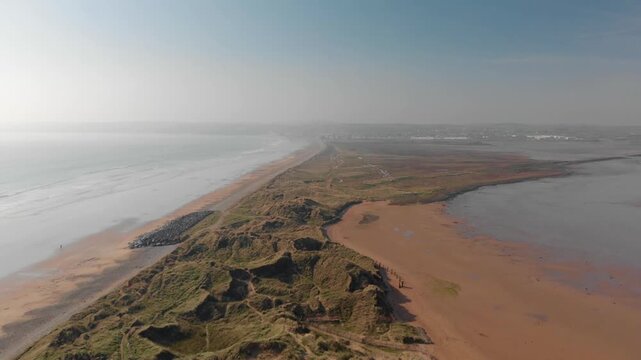 Drone camera glides smoothly over serene coastal landscape, revealing peaceful natural beauty and expansive open spaces for travel inspiration and wellness escapes.