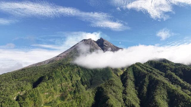 Aerial view footage of Mount Merapi Yogyakarta, beautiful bright blue sky, slightly covered in clouds.