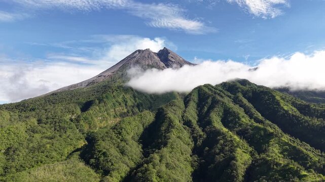 Aerial view footage of Mount Merapi Yogyakarta, beautiful bright blue sky, slightly covered in clouds.