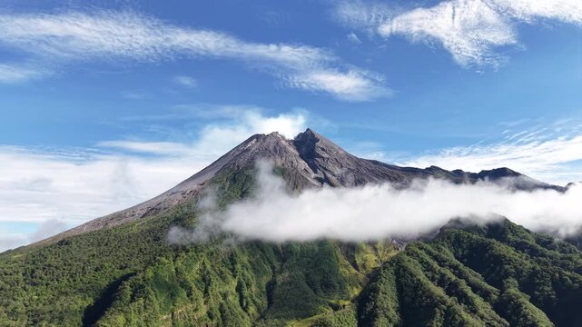 Aerial view footage of Mount Merapi Yogyakarta, beautiful bright blue sky, slightly covered in clouds.