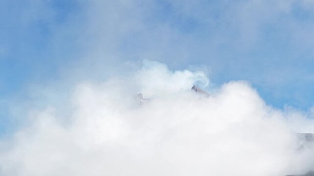 4K aerial footage shows the peak of Mount Merapi in Yogyakarta covered in thick clouds, with clear blue skies.