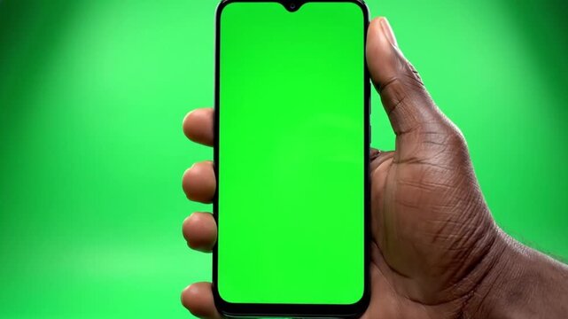 Hand holding smartphone with green screen isolated on green background