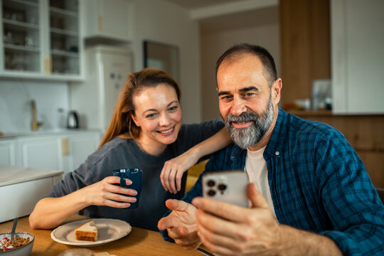 Smiling couple looking at smartphone in kitchen
