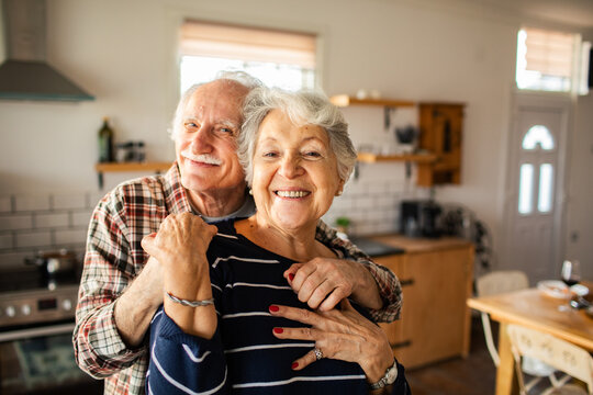 Smiling senior couple embracing in home kitchen