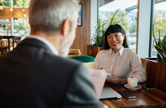 Smiling businesswoman meeting with colleague in modern cafe