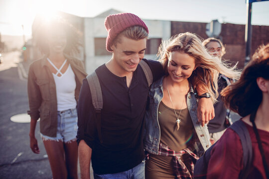 Young friends walking together on a city street at sunset