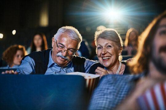Happy senior couple watching a movie at the cinema