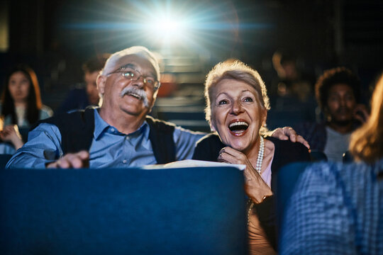 Happy senior couple watching movie at cinema