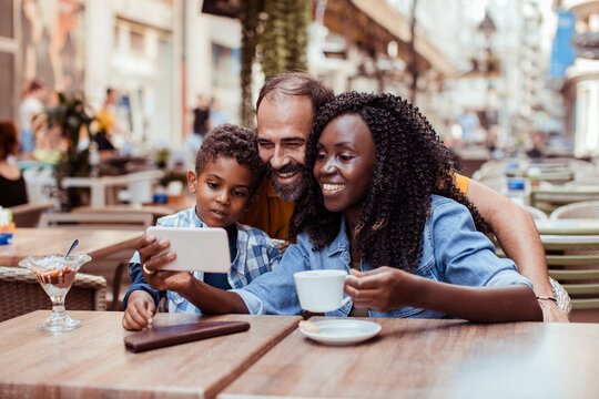 Parents and son taking selfie at outdoor cafe