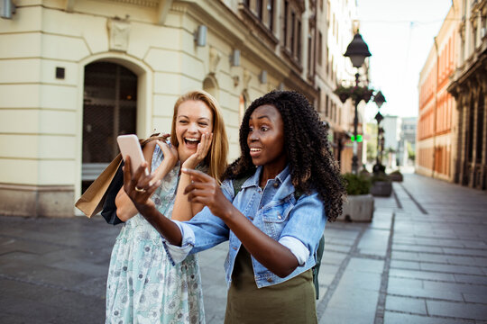 Two friends taking selfie on city street