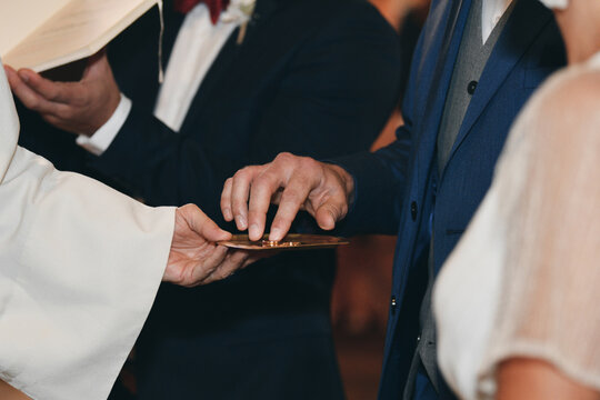 A priest presenting wedding rings on paten during sacred church ritual