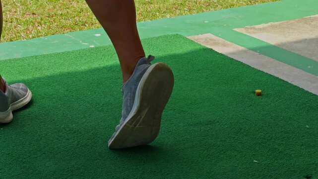 Close view of Woman striking Golf ball on green turf with motion blur of club and clear stance, Action and Precision in Sport