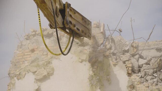 Excavator hydraulic hammer smashes the wall of the building