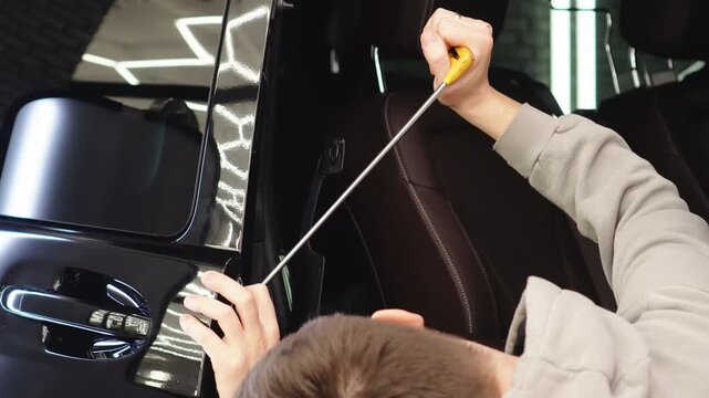 PDR. Process of paintless dent repair on car body. The mechanic at the auto shop with tools to repair dents in car body. Body repair. A specialist repairs a dent on the car body without painting. 