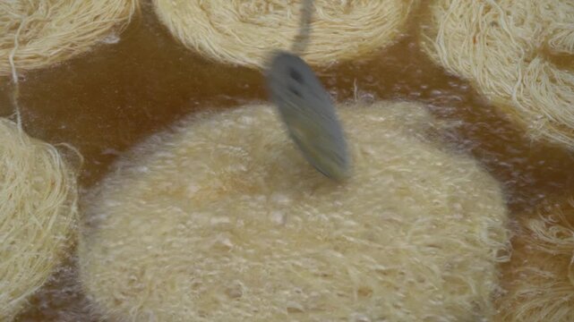 Chef deep-frying kataifi pastry in hot bubbling oil, preparing a traditional middle eastern dessert like kunafa or kadayif for a sweet and crispy treat
