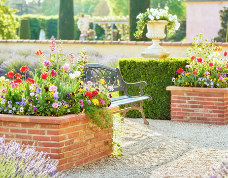 Colorful English garden with bench and brick planters