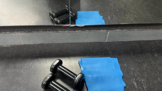 Black dumbbells placed in front of mirror with reflection. Strength training, fitness motivation, gym workout, exercise equipment and healthy lifestyle concept.