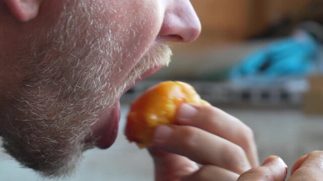Beard man eating, close-up of a person enjoying a juicy peach