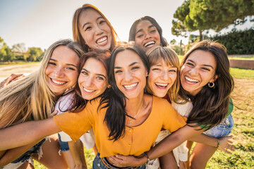 Obraz premium Multi ethnic group of young women hugging outside - Happy girlsfriends having fun laughing out loud on city street - Female community concept with cheerful girls standing together - Women power