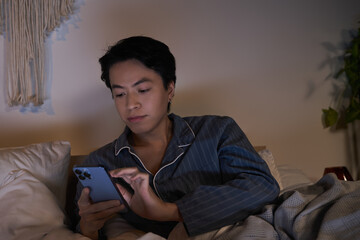 Fototapeta premium Modern man enjoys relaxed evening with phone in cozy apartment setting
