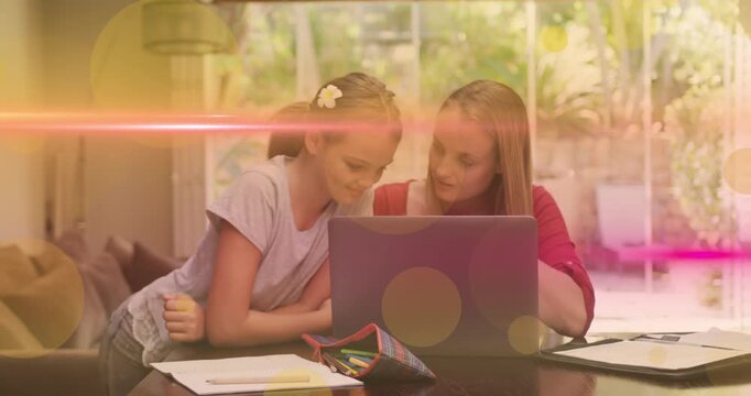 Animation of light moving over happy caucasian daughter and mother working on laptop at home