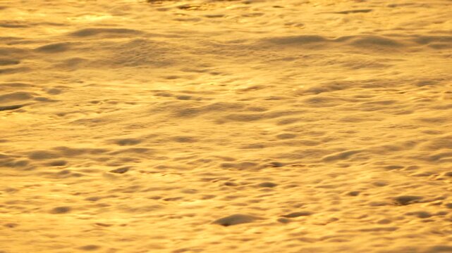 Waves, beach, sunset, golden water flowing onto sand, peaceful nature scene