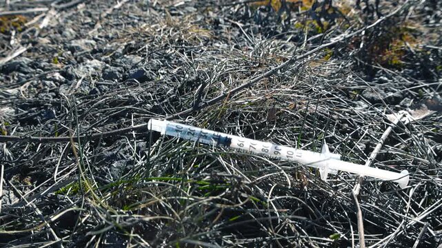 Used syringe lying on the ground representing drug abuse