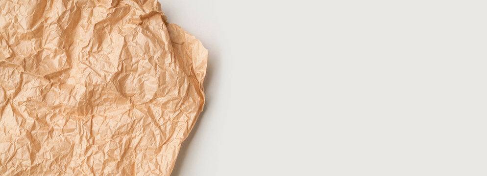 Crumpled brown paper, parchment, kraft paper on gray background top view. Abstract background, baking paper texture, empty space for text or inscriptions. Backdrop for your design