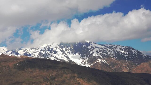 Mountains show snow and clouds in the sky above