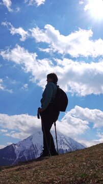 Hiker on a sunny mountain trail. vertical video
