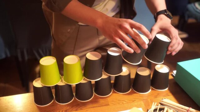 Pyramid of plastic cups on wooden table with green background. Party game
