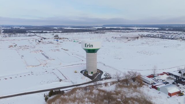 Water Tower And New Housing Neighbourhood Development During Winter In Erin, Ontario. Orbiting Aerial Shot.