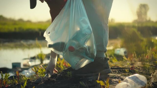 An eco-conscious volunteer meticulously gathers plastic bottles and waste on the riverbank at dusk, sorting recyclables to promote sustainability and conservation