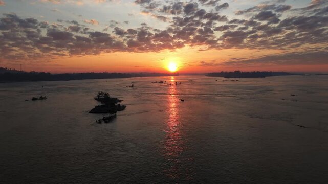 Drone shot pushing forward towards the rising sun over the Mekong river on the border between Laos and Cambodia.