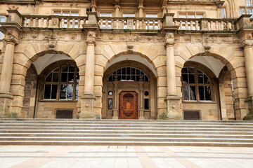 Obraz premium Detailed view of a historic town hall facade with columns, arches and an ornate entrance on a city square.