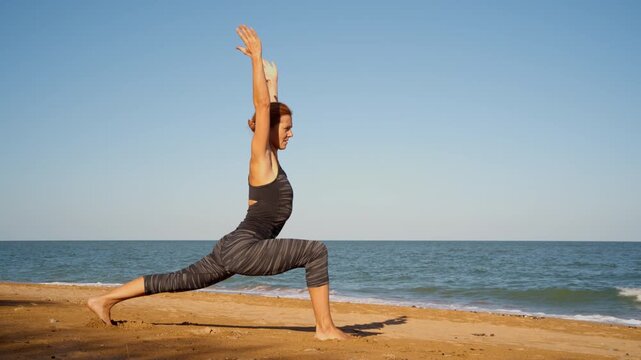 Woman practicing yoga side lunge pose on sunny beach ocean background. Healthy lifestyle physical activity connection with nature respiration mindfulness concept.
